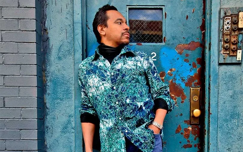 Jay Rodriguez Sierra in a patterned jacket in front of a blue door.