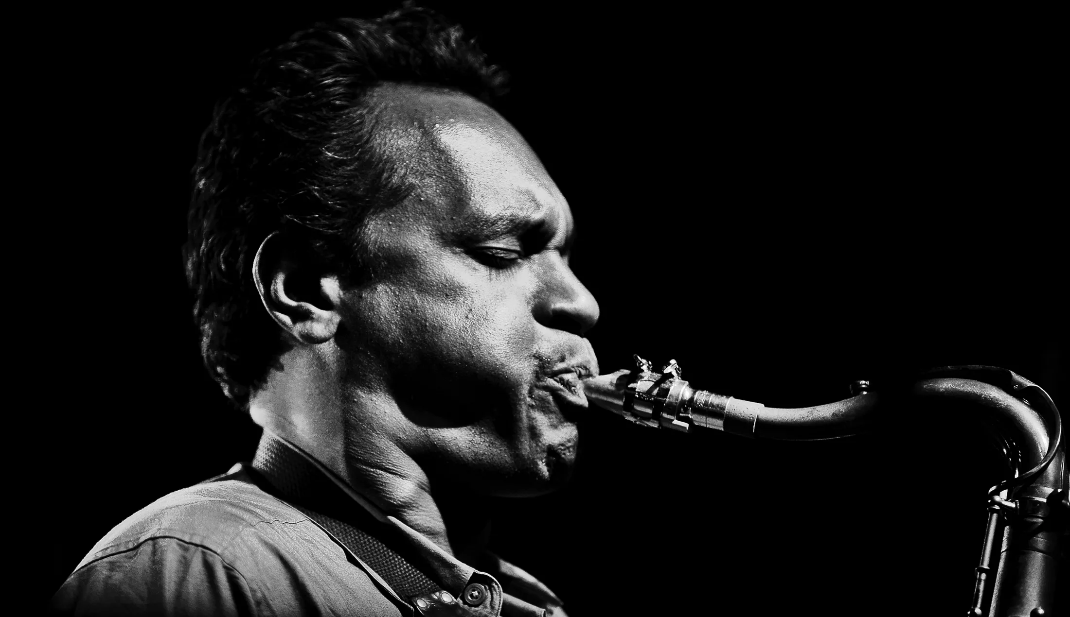 Black-and-white profile of Jay Rodriguez Sierra playing tenor saxophone.